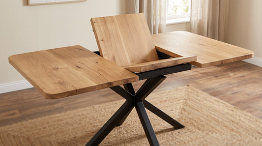 Solid oak extendable dining table with an open butterfly leaf extension mechanism and black metal spider base.