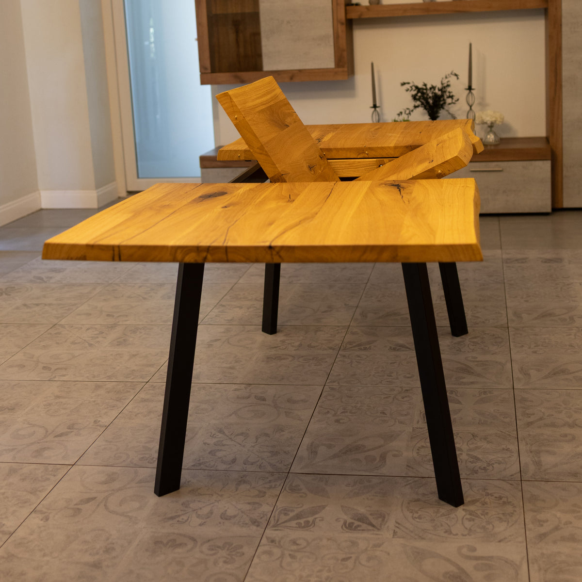 A rustic wooden dining table with a live-edge top and black metal legs, shown in a modern dining room setting.