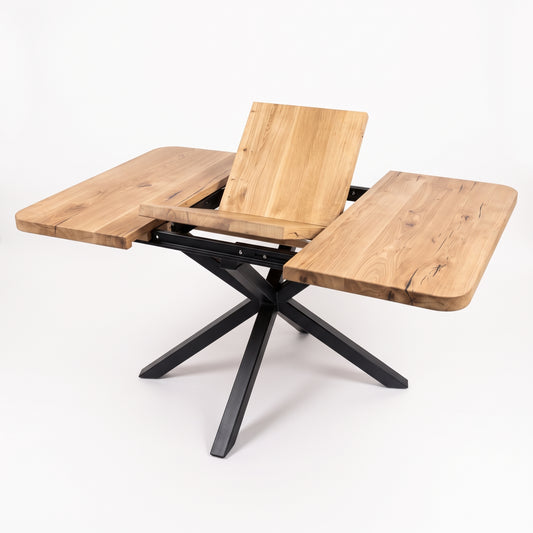 A modern outdoor dining table with a natural wood finish and a black metal X-frame base, shown with its center panel raised and side wings extended on a white background.