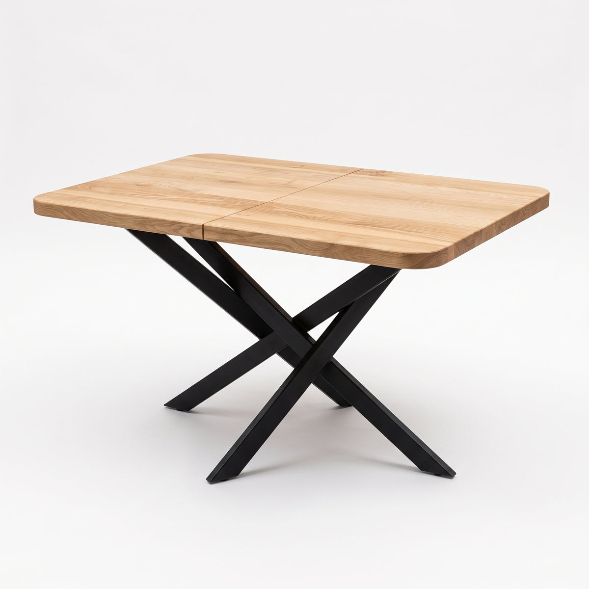 A rectangular wooden table with rounded corners and a black metal X-shaped base, shown on a clean white studio background.