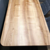 A rectangular wooden conference table with rounded corners and a light natural wood grain finish, shown with dark gray upholstered chairs in an indoor room setting.