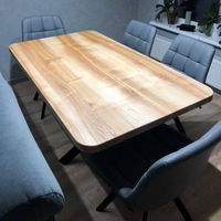 A rectangular wooden conference table with a light natural wood finish, surrounded by gray upholstered chairs in a modern office or meeting room setting.