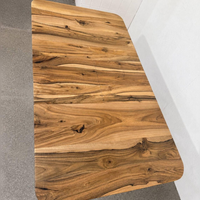 A rectangular wooden tabletop with rounded corners, showcasing a rich natural wood grain pattern in warm brown and golden tones, photographed in a clean indoor setting.