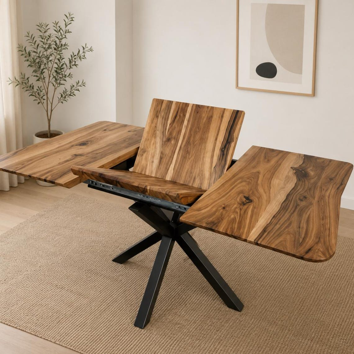 A modern rectangular dining table with a live-edge wood top and black metal pedestal base, shown in a staged interior with one side panel extended and a plant in the background.